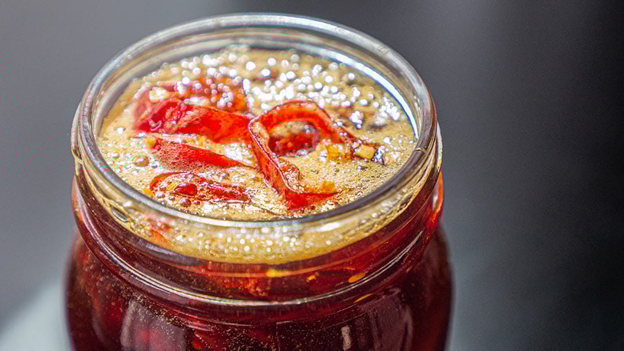 chili peppers submerged in a jar of honey