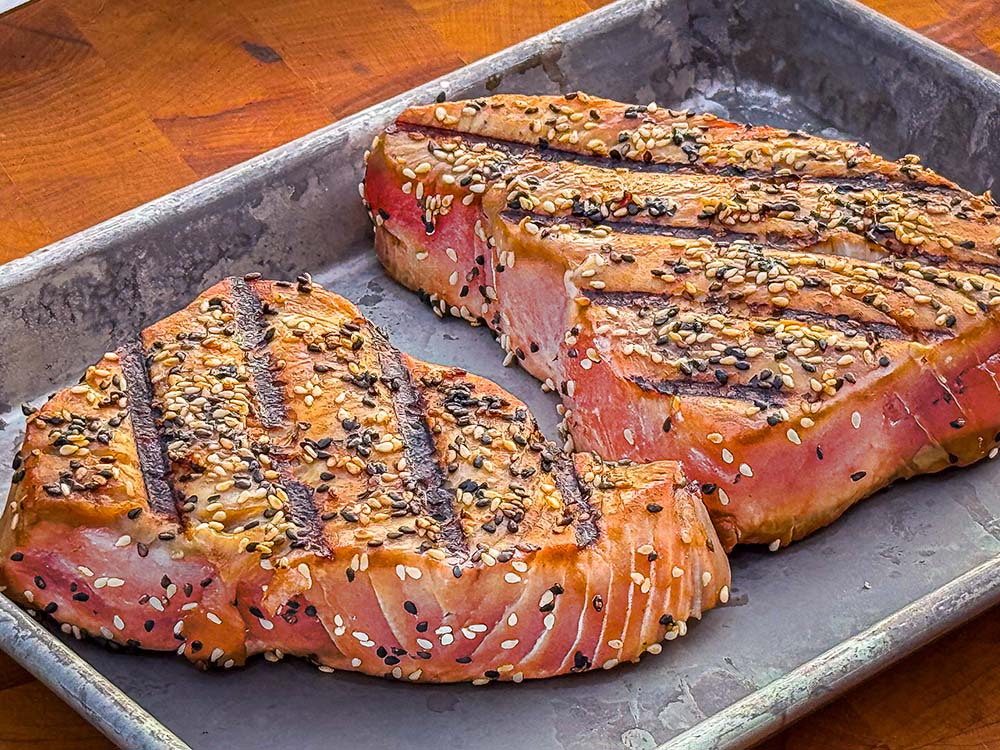 Grilled Tuna steaks rest on a small commercial baking tray.
