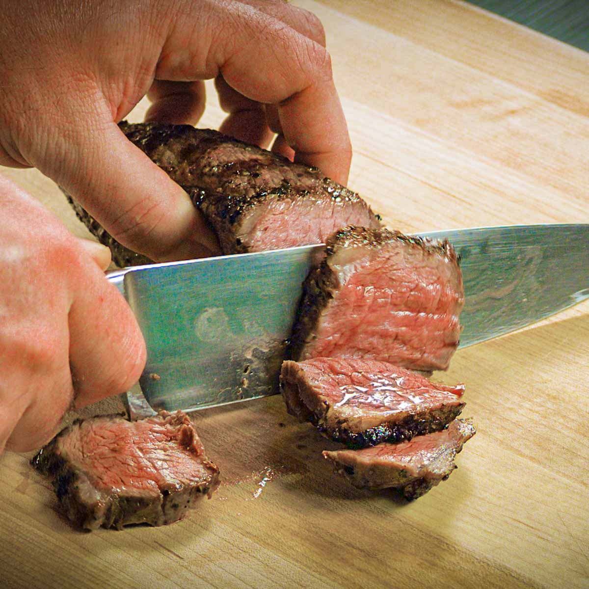 A knife slices perfect medium-rare picanha steak.