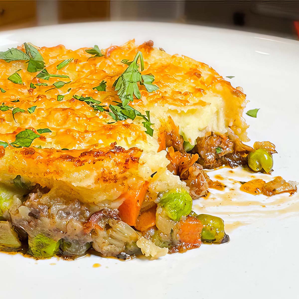 Beautiful Shepherds Pie with a bite taken out of it sits on a white plate.
